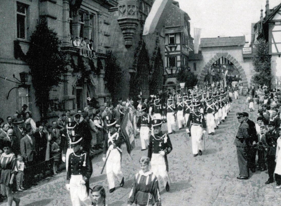 Der Festzug 1950 zieht mit der Bürgerwehr Bretten von West nach Ost auf dem Marktplatz ein.